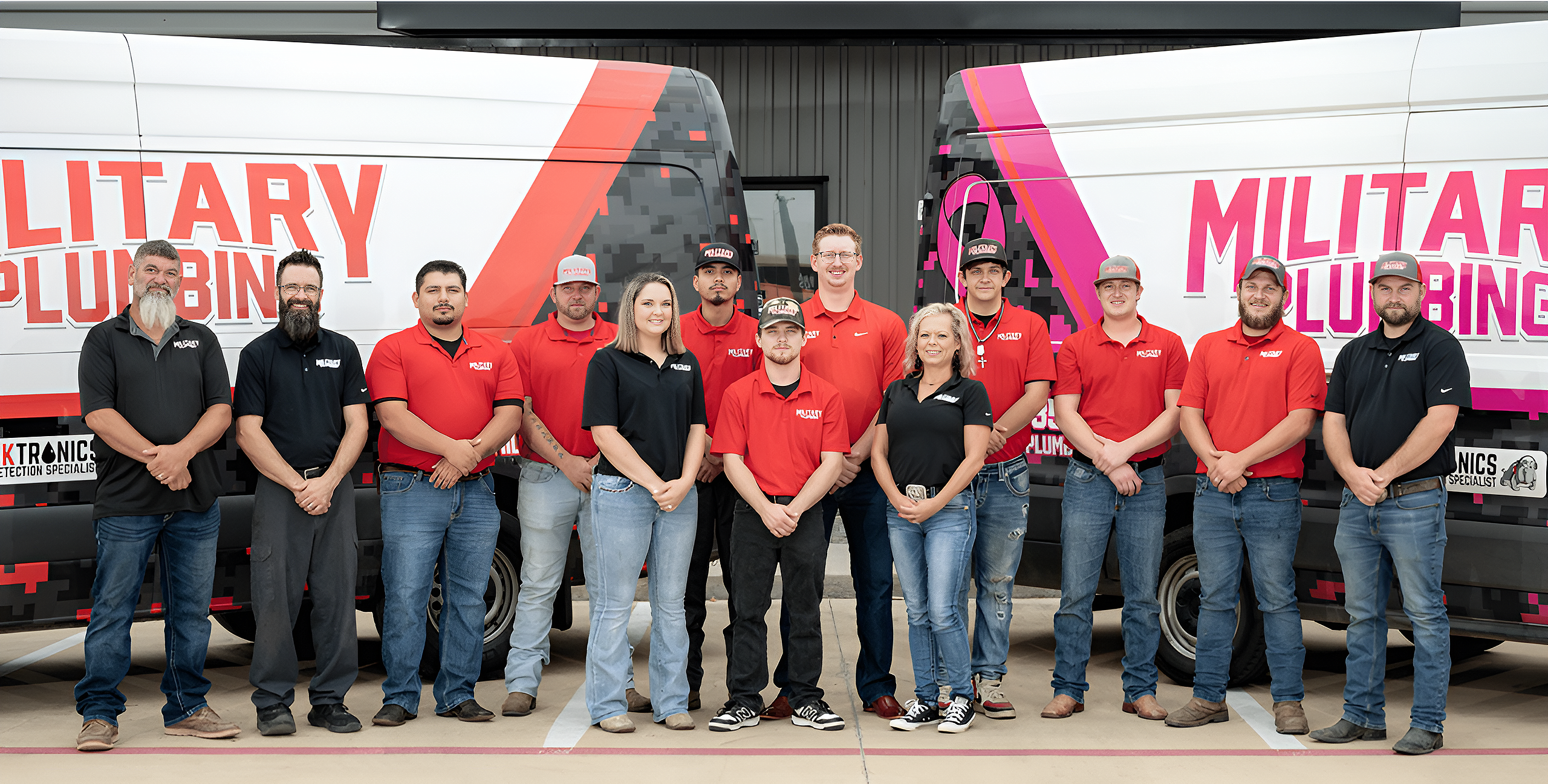 Military Plumbing team in front of branded company vehicles